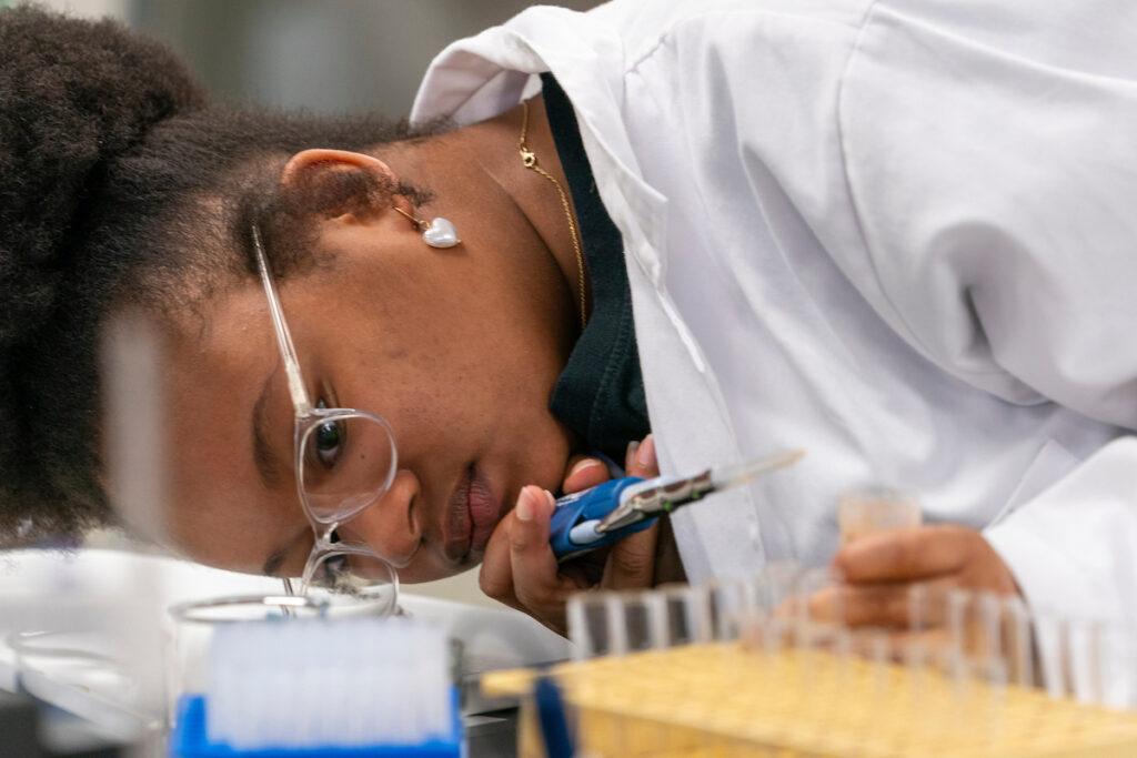 A female researcher eyeballing the contents of a set of beakers