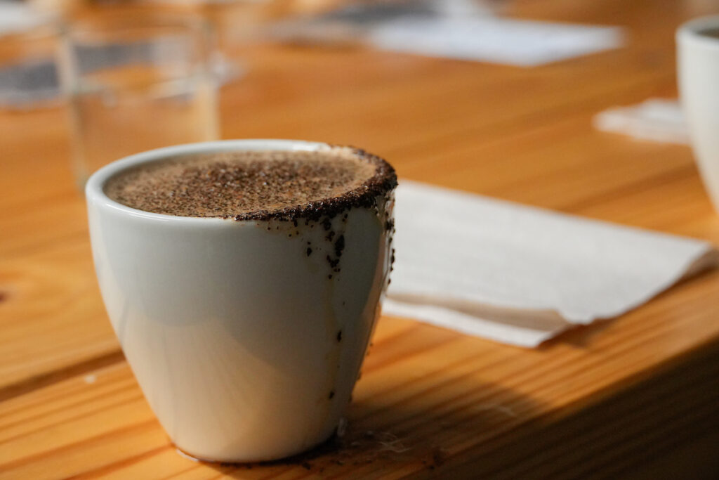 Cup overflowing with coffee and ground coffee beans
